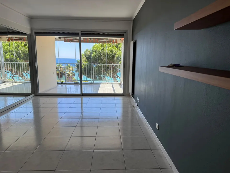 Living area with terrace access and pine-framed sea view