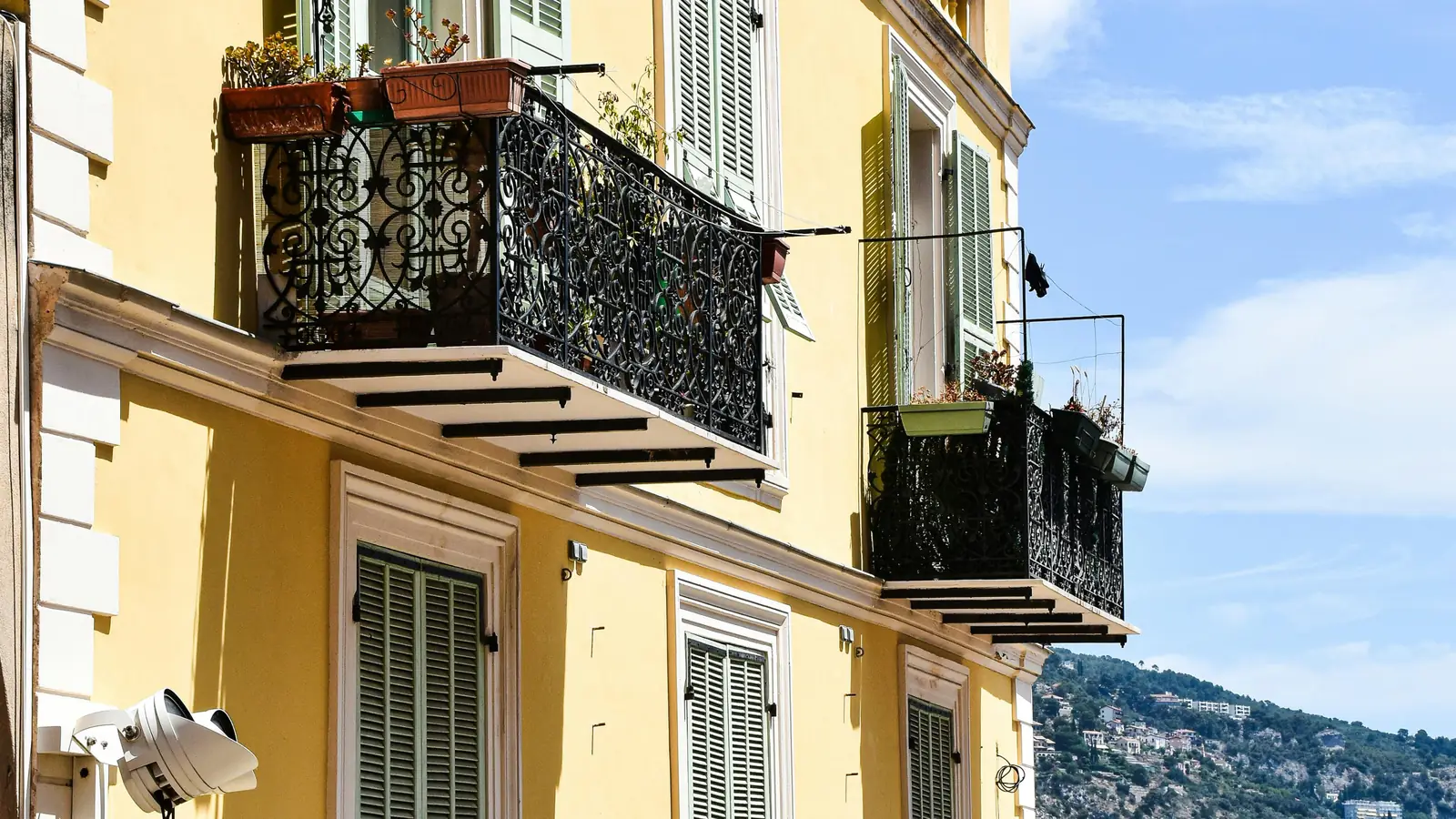A yellow facade with wrought-iron balconies and green shutters on the French Riviera