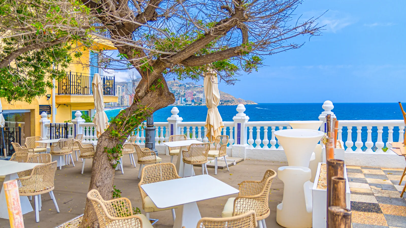 A café terrace with a white balustrade overlooking the Mediterranean