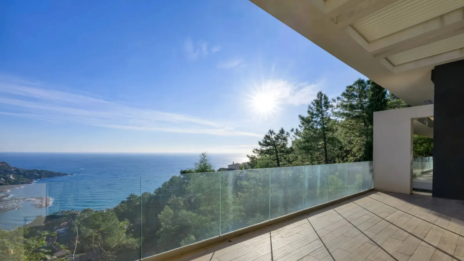 A modern villa terrace with a glass balustrade overlooking the Mediterranean