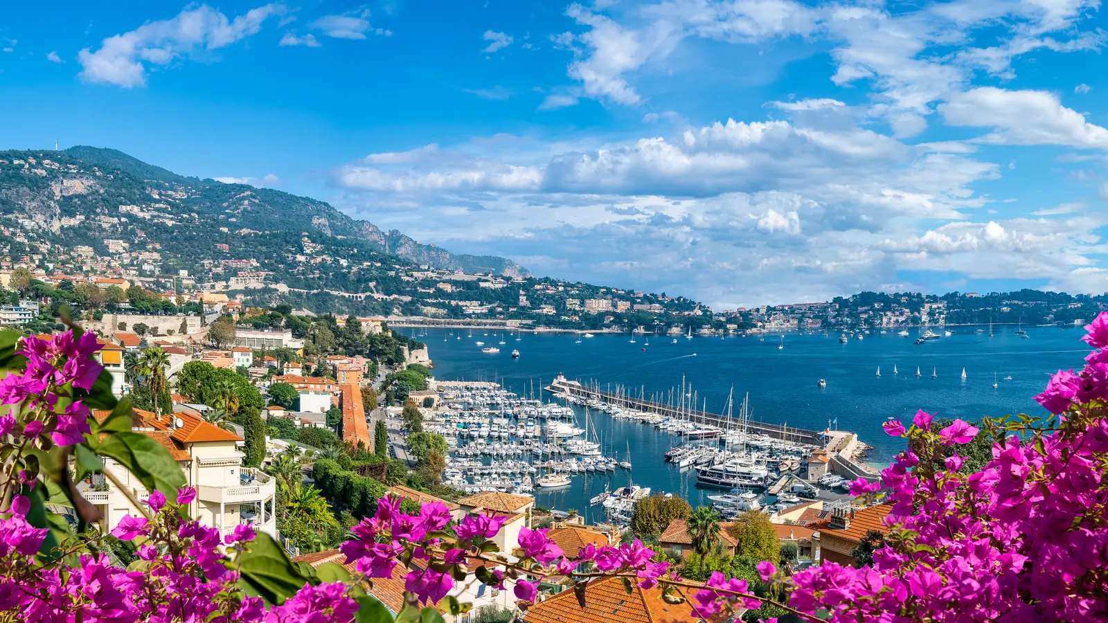 The harbor of Villefranche-sur-Mer with yachts, bougainvillea and hillside homes above the bay