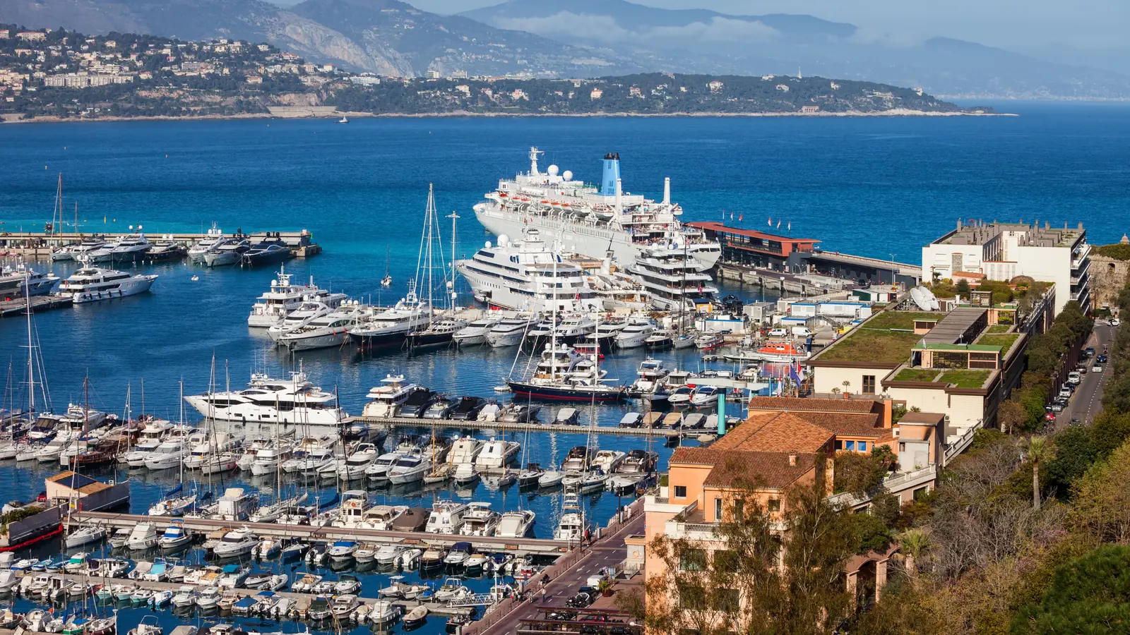 Yachts and a cruise ship in Port Hercule, with the coastline beyond