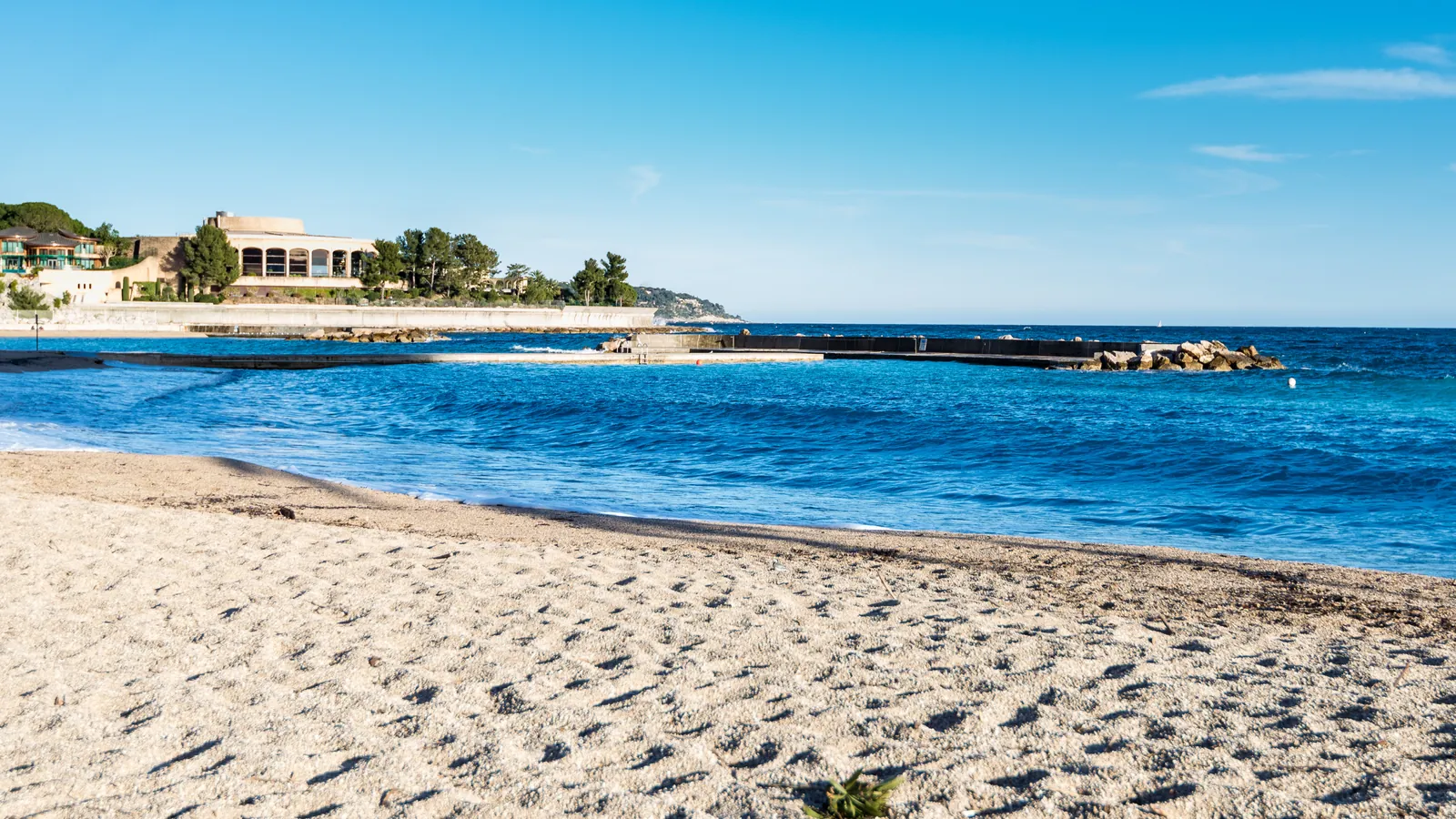A sandy Mediterranean beach on the seafront near Monaco, with clear blue water
