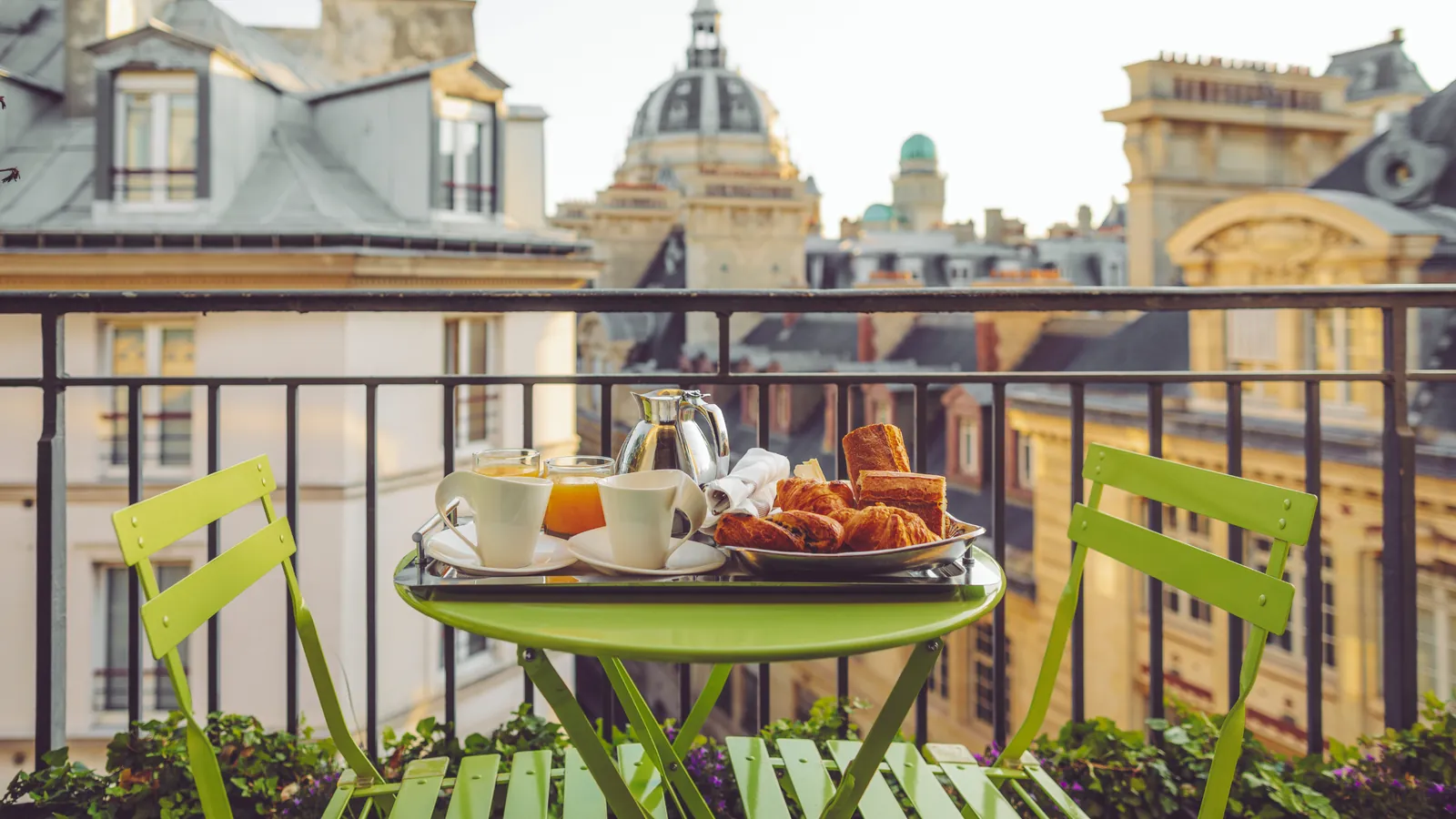 Breakfast on the balcony of a Paris apartment, overlooking the city's rooftops and domes