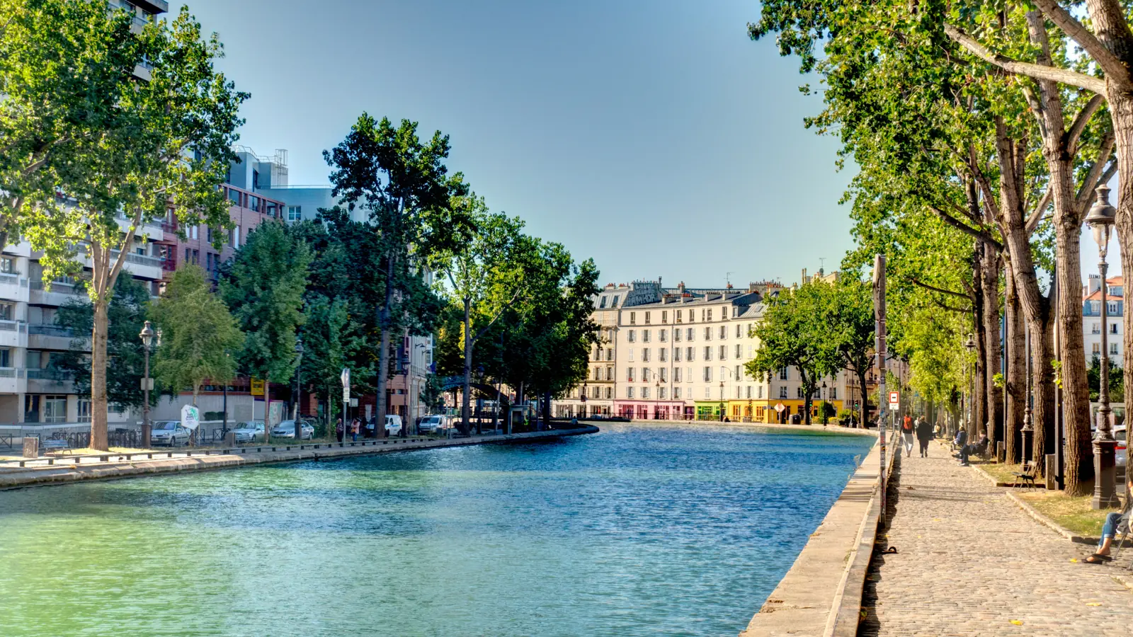 A tree-lined canal in north-east Paris with apartment buildings along the quay