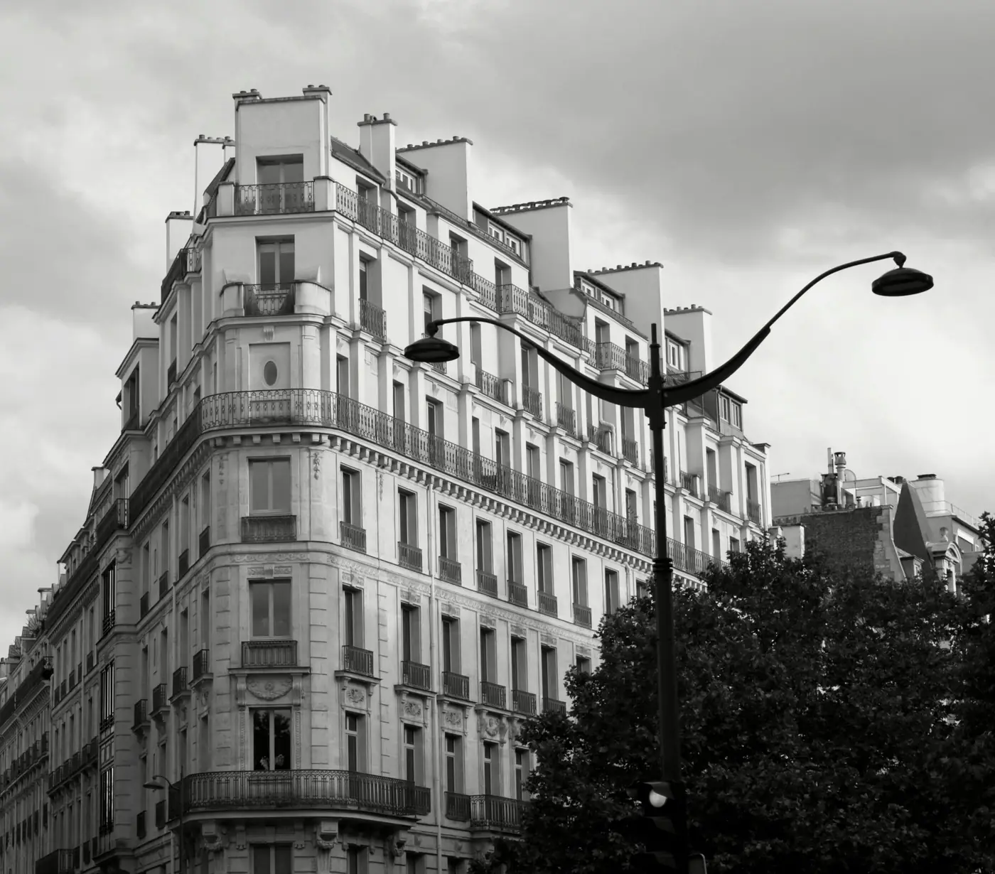 A Haussmann apartment building on a Paris street corner, in black and white