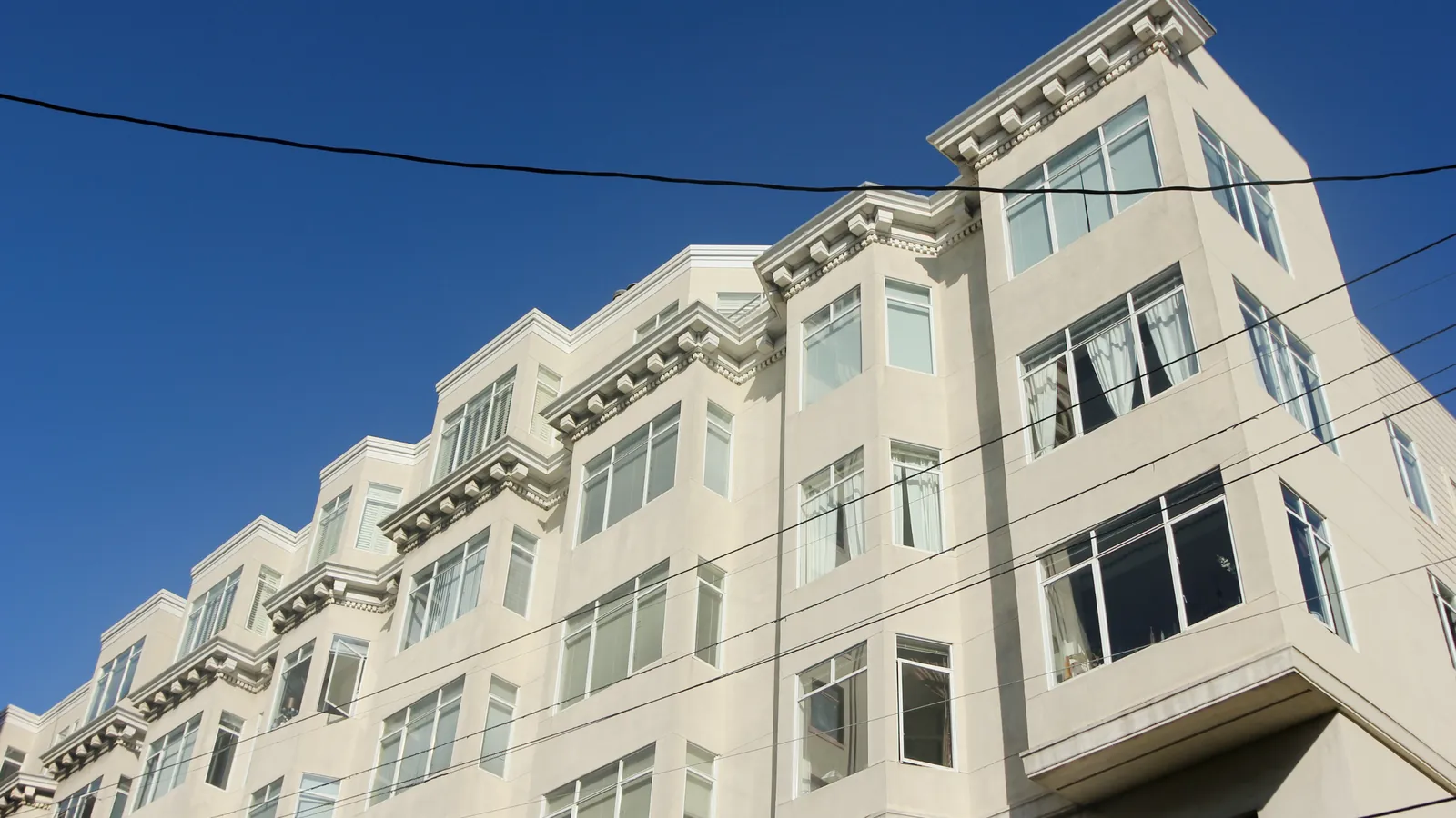 A San Francisco apartment building with stacked bay windows under a clear blue sky