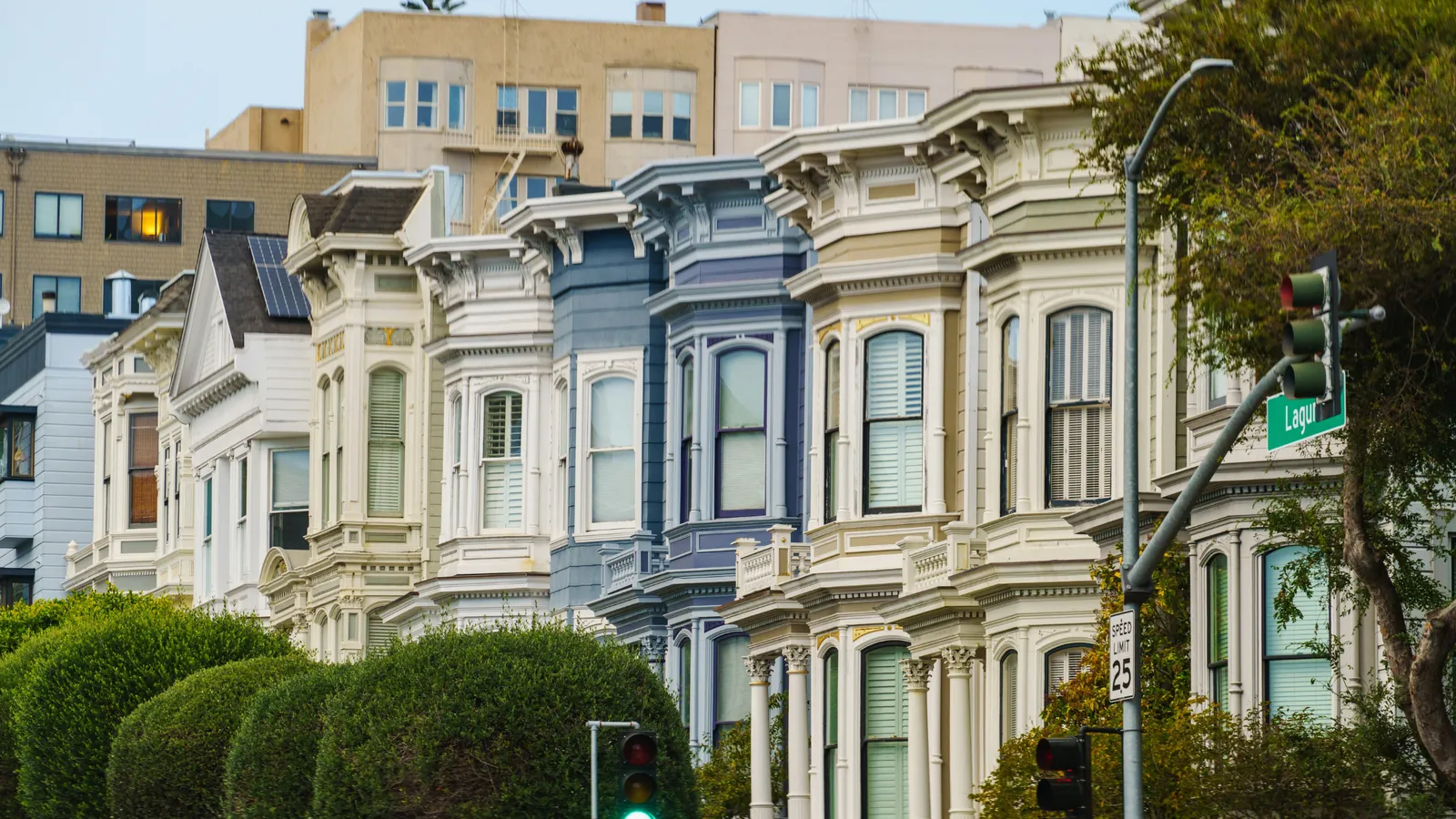 A row of painted Victorian houses at a San Francisco street corner