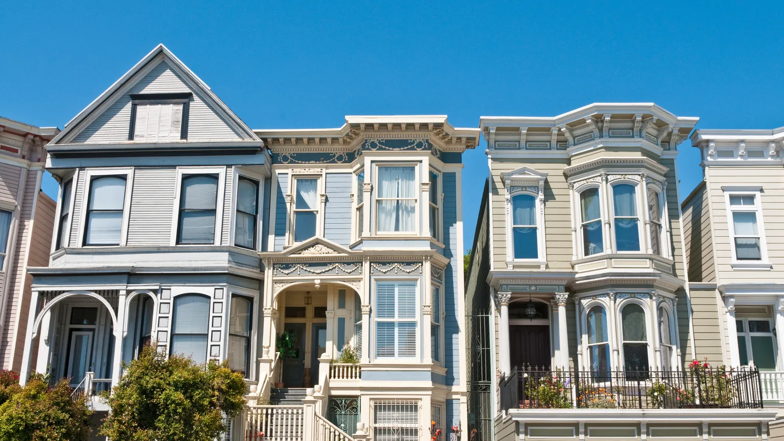 Restored Victorian homes with bay windows and front steps on a sunny San Francisco street